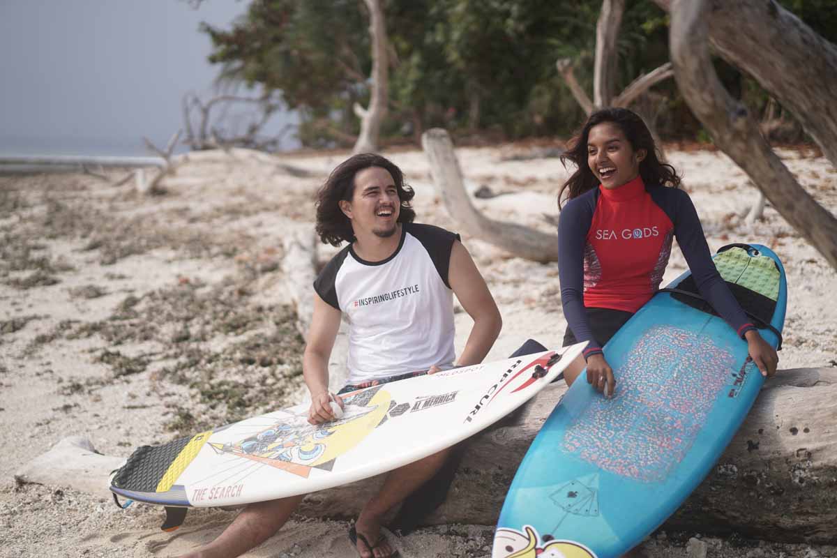 Salini Rengganis dan David John Schaap sedang waxing papan surf dengan penuh tawa